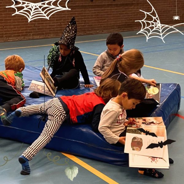 un gruppo di bambini e bambine travestiti da halloween leggono dei libri durante il camp herfstvakantie 2023