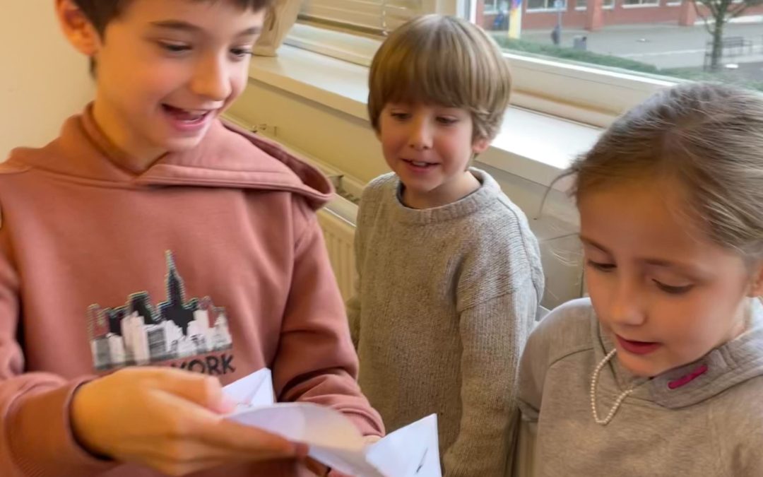 Tre bambini aprono felici una lettera per il progetto Amicɜ di Penna
