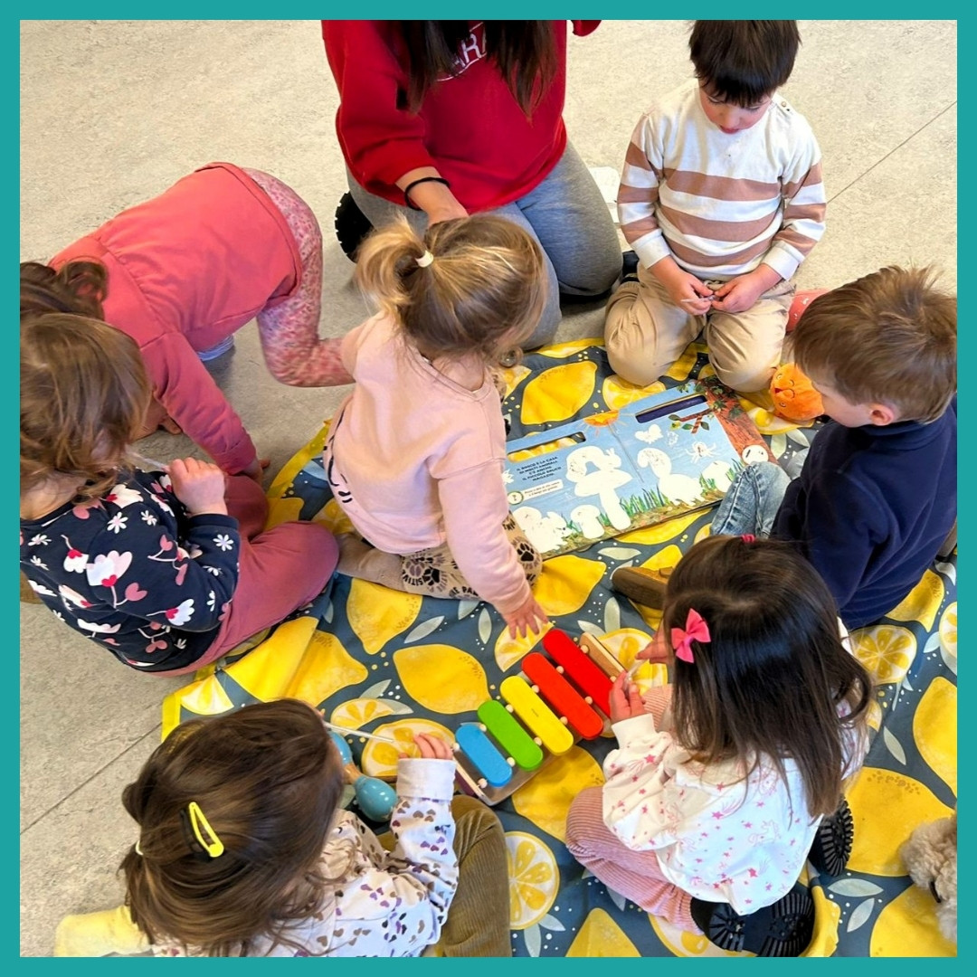 een groep kinderen van 3-4 jaar oud speelt op een tapijt met boeken en klein gereedschap