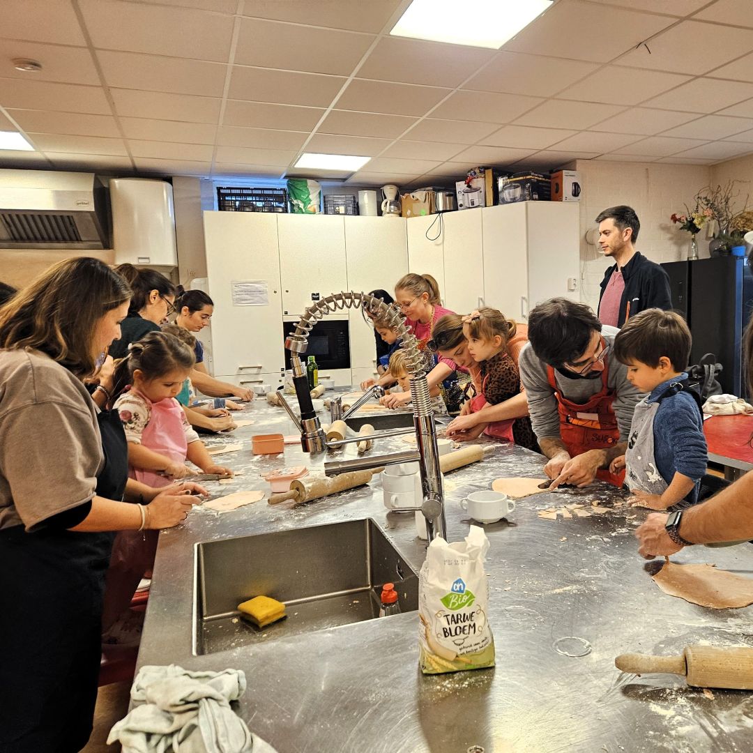 groep ouders en kleine kinderen samen koken in een grote keuken