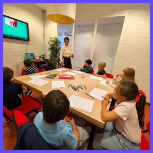 Pedagoog geeft les aan 8 kinderen die rond een tafel zitten